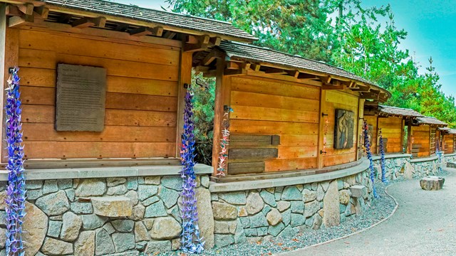 Wooden and stone memorial that curves along a sidewalk.